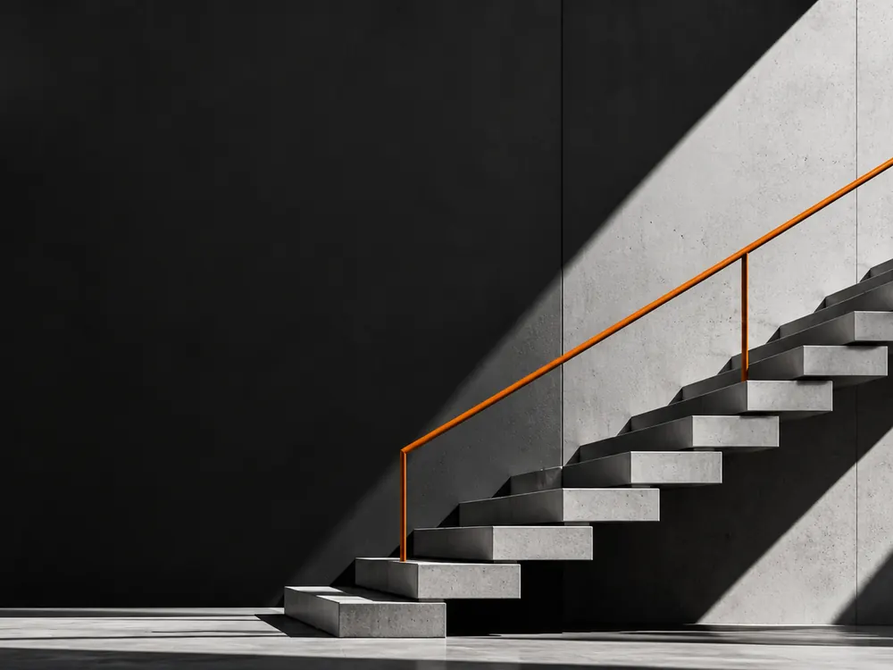 Concrete staircase with an orange handrail